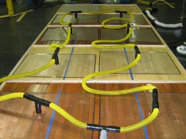 Drying mats and yellow hoses pulling water out of a hardwood floor